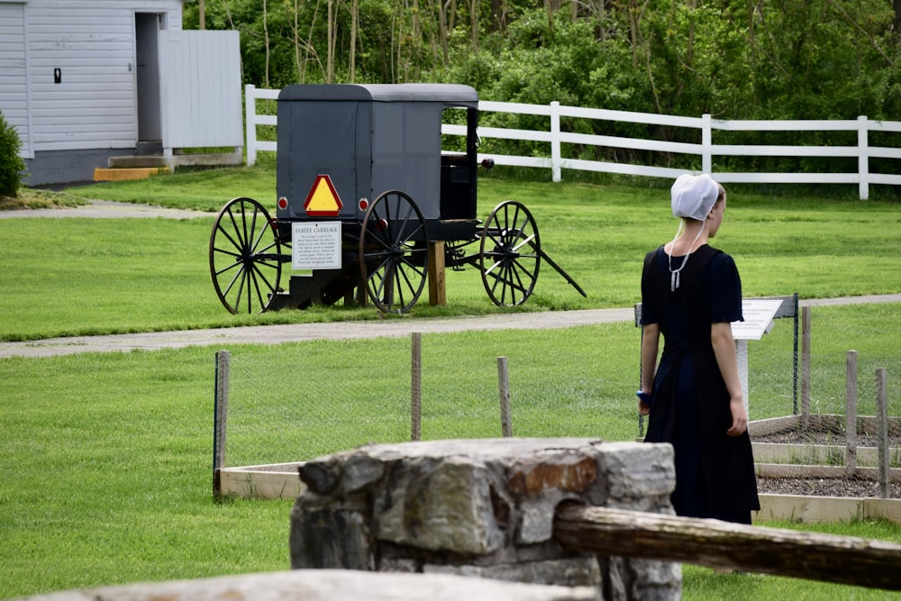 a woman standing in front of a horse drawn carriage