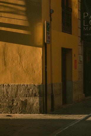 A quiet street corner in India bathed in soft morning light, with subtle shadows playing on textured walls.