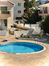 A sparkling clean swimming pool surrounded by a well-kept garden in a residential area.
