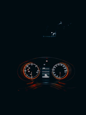 A sleek racing game dashboard with speedometer glowing crimson red against a dark background.