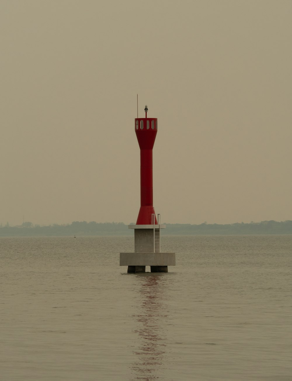 a red light house sitting in the middle of a body of water