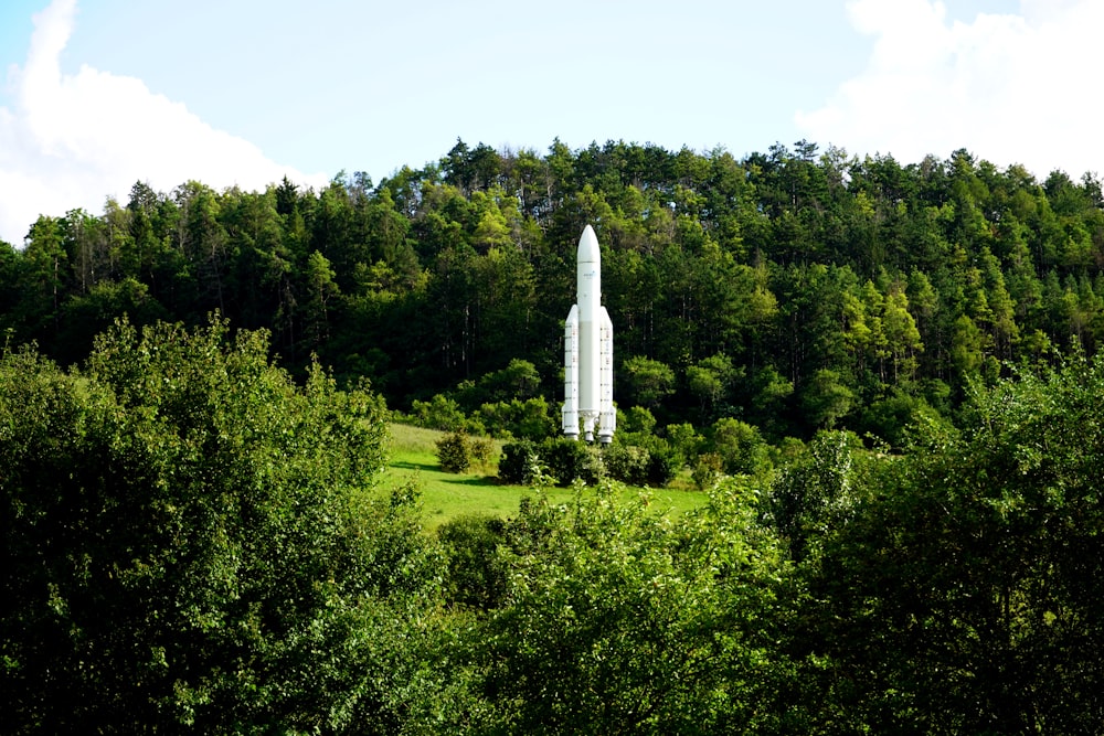a large white rocket sitting in the middle of a forest
