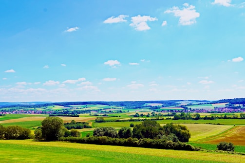 A lush green gated farmland community with cottages and fruit trees under a clear blue sky.