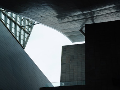 A geometric architectural scene with angular structures and modern design, where overlapping panels and open spaces create unique shadows and textures.
