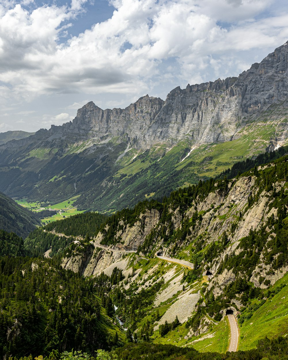 a scenic view of a mountain valley with a winding road