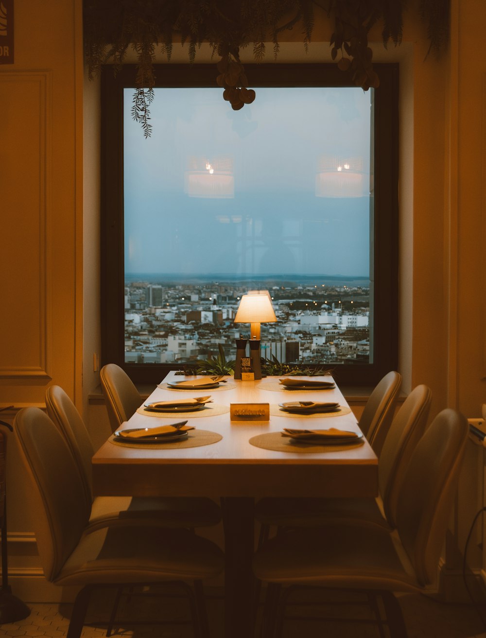 Una mesa larga con ajustes de lugar frente a una ventana