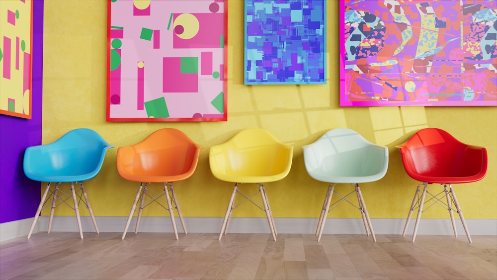노란 벽 앞에 줄지어 앉아 있는 형형색색의 의자들