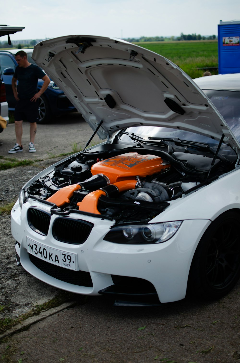 a white car with an orange hood parked on the side of a road