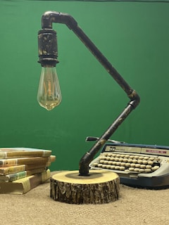 A stack of well-read books next to a vintage typewriter on a wooden desk.