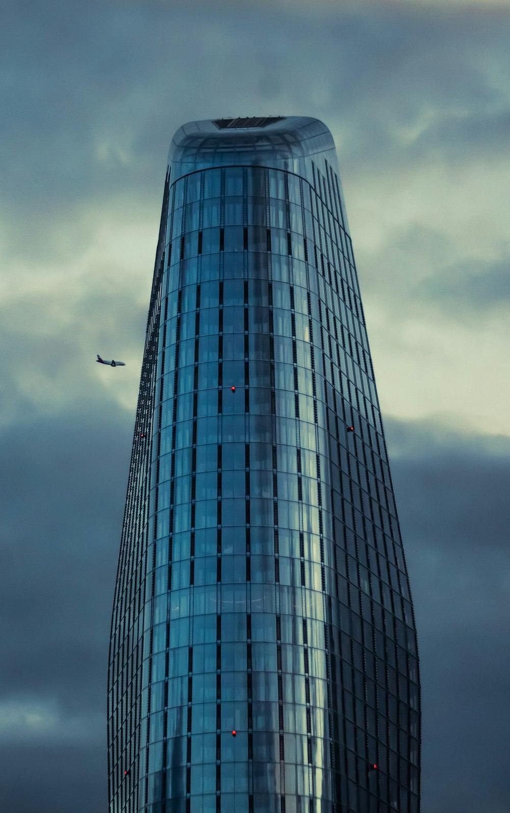Un edificio muy alto con un avión volando en el cielo