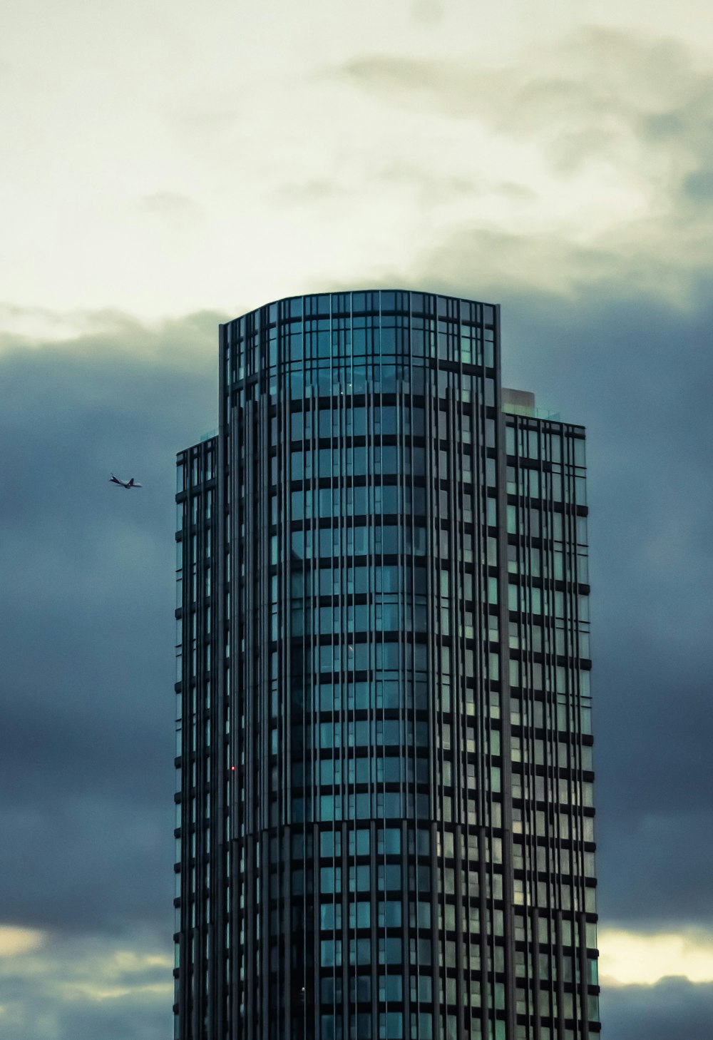 a very tall building with a plane flying in the sky