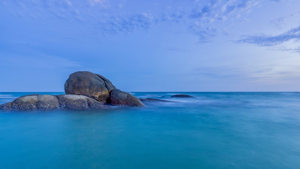 a large rock in the middle of a body of water