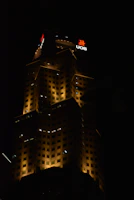 Nighttime exterior of a luxury building illuminated with subtle golden lighting highlighting architectural details.
