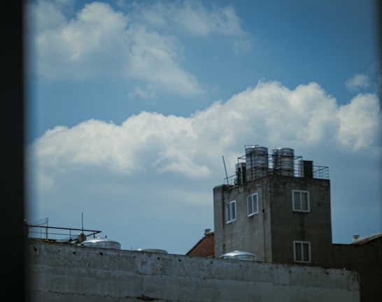 A technician servicing a water tank on a rooftop under a clear sky.