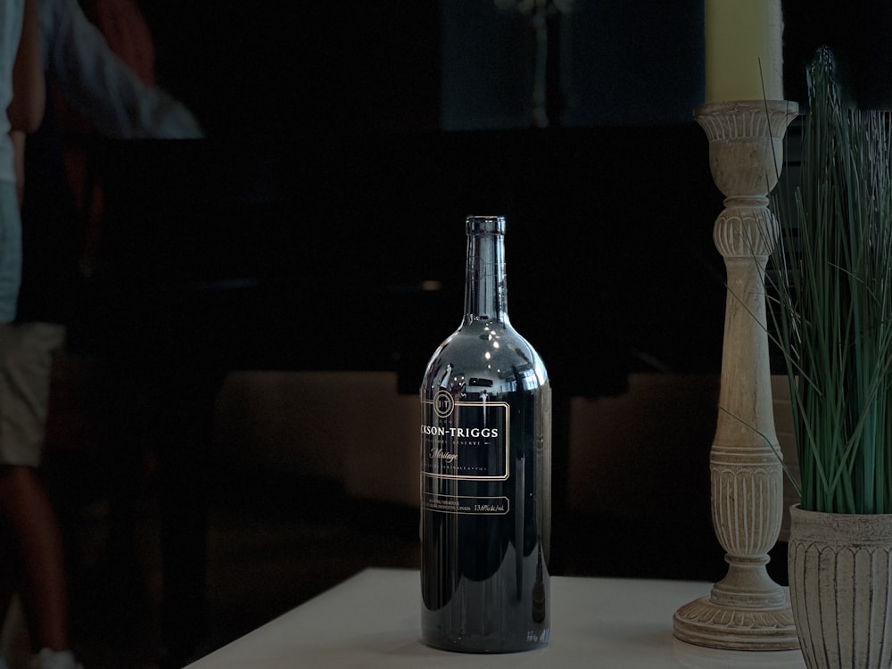 a bottle of alcohol sitting on a table next to a vase