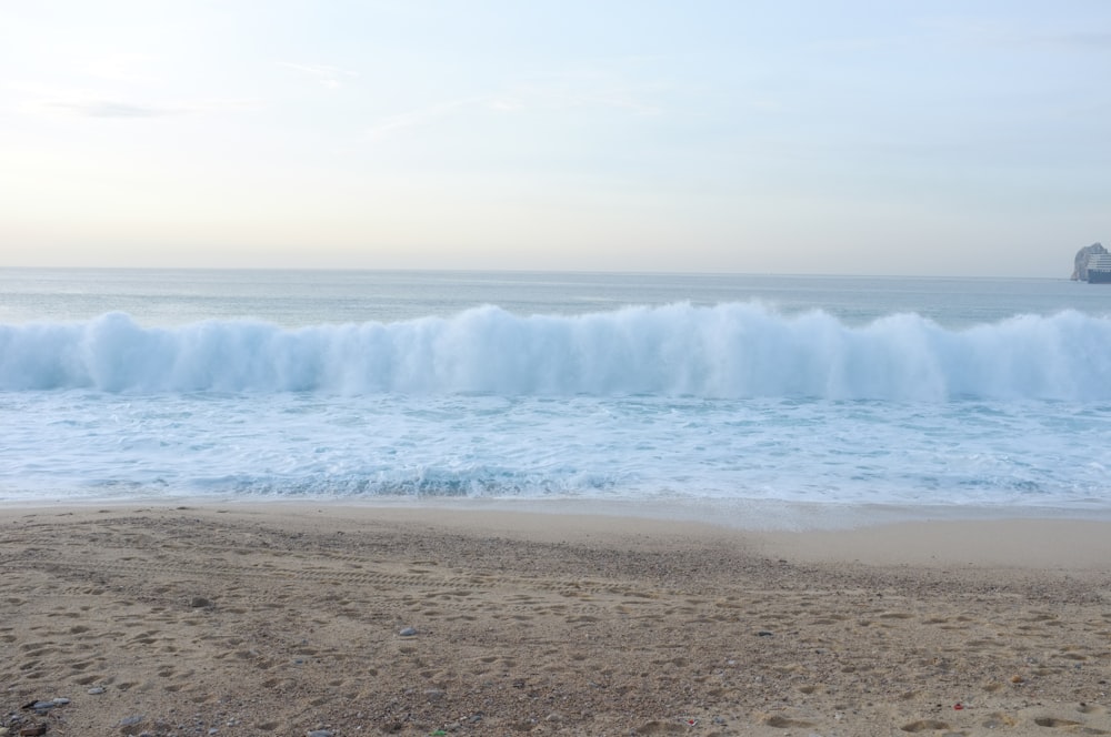 a beach with a large wave coming in to shore