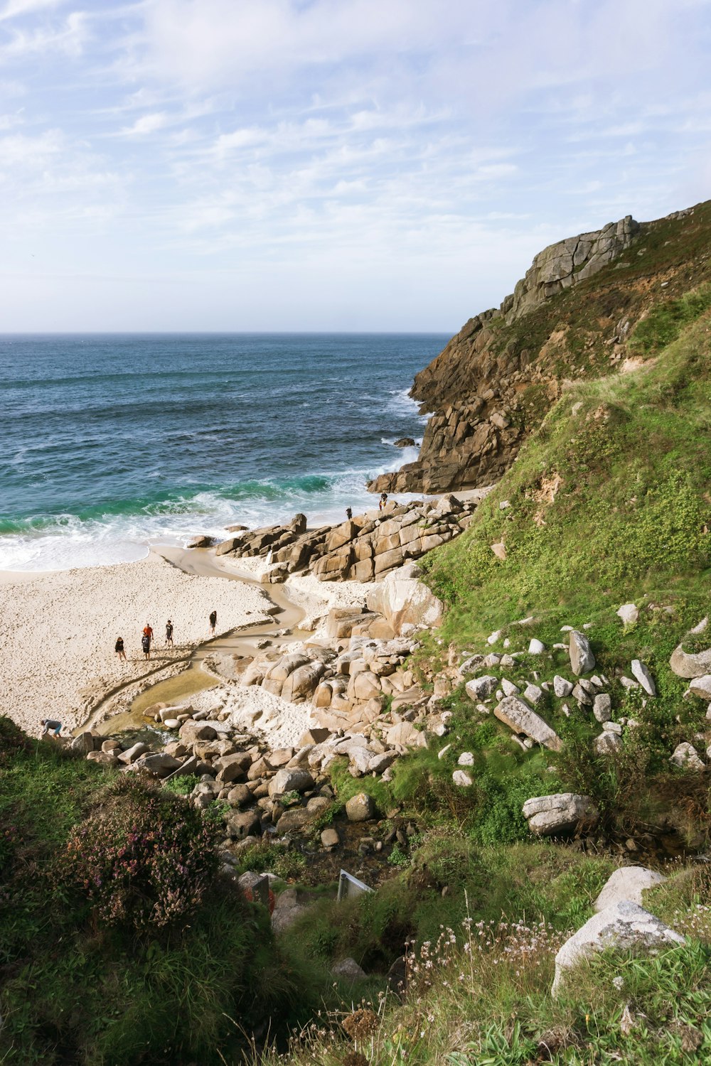 a group of people standing on a beach next to the ocean