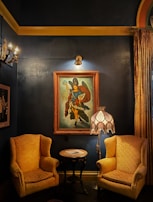 A cozy corner with plush red velvet chairs and a glowing gold lamp casting a warm light.