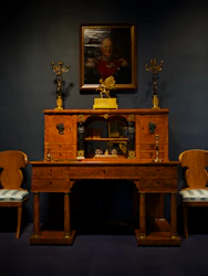 Elegant office desk with a sleek gold-accented phone and a black leather notebook beside a window overlooking Antigua's harbor at dusk.