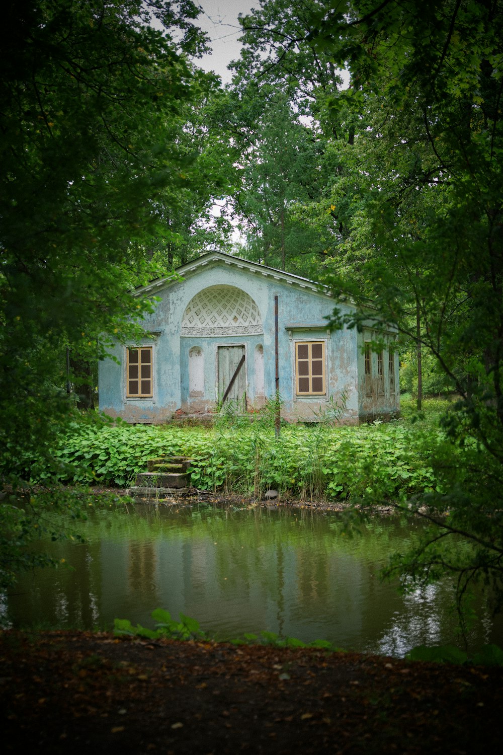 a small blue building sitting next to a pond