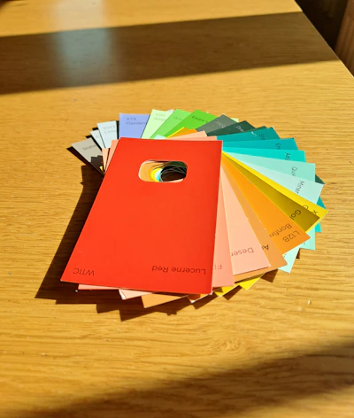 Close-up of colorful paint swatches fanned out on a wooden table, inviting customers to choose their perfect shade.