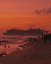 A luxurious cruise ship sailing past a tropical island at sunset.