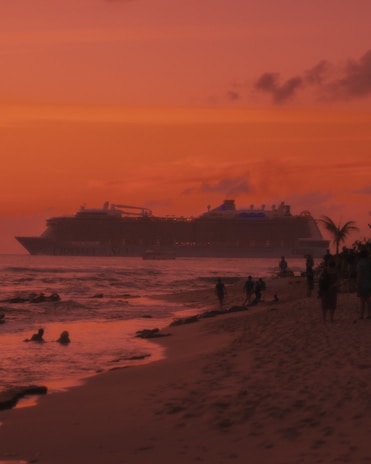 A stunning Royal Caribbean ship sailing past a tropical island at sunset.