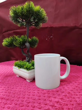 A cozy ceramic mug with pastel pink glaze resting on a wooden table beside a small succulent plant.
