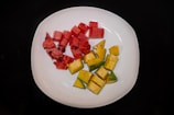 Bright IQF mango cubes neatly arranged on a white plate with a green leaf garnish