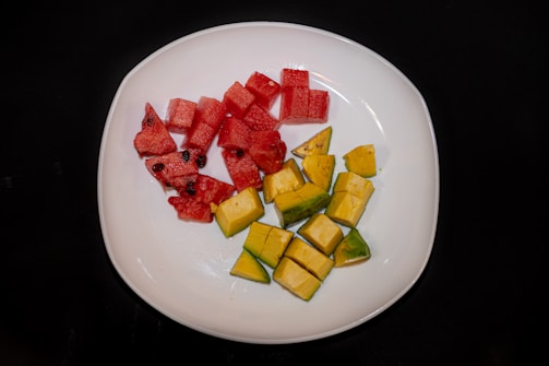 Bright IQF mango cubes neatly arranged on a white plate with a green leaf garnish
