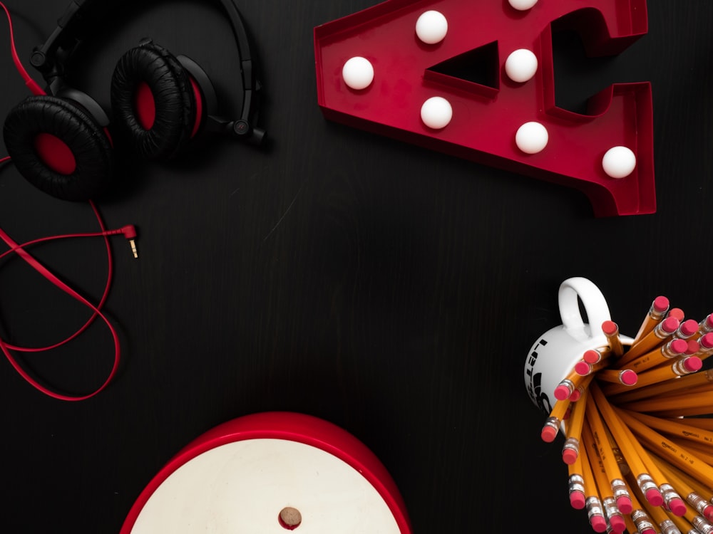 a black table with headphones, pencils, and a neon sign