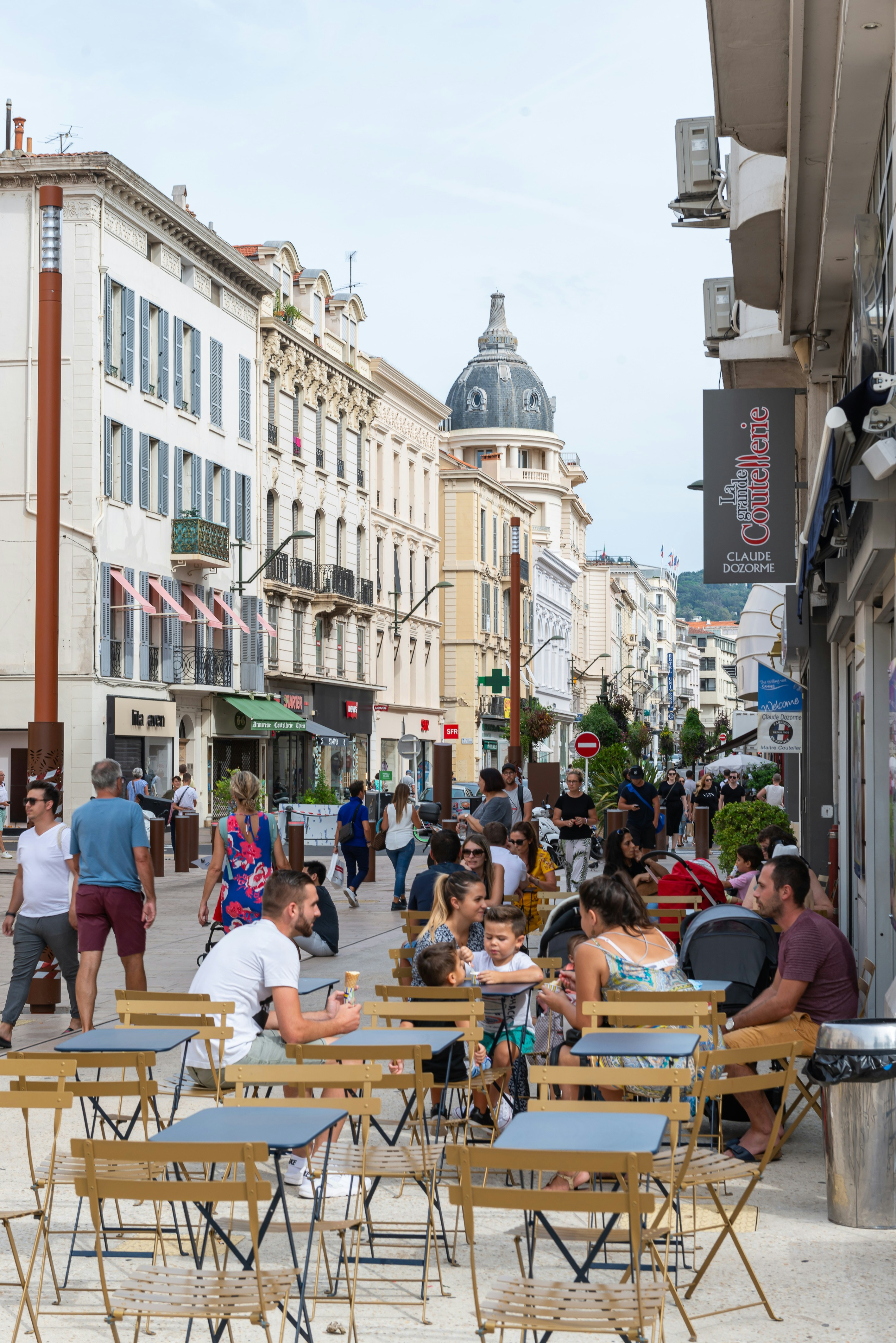 a group of people sitting at tables on a sidewalk