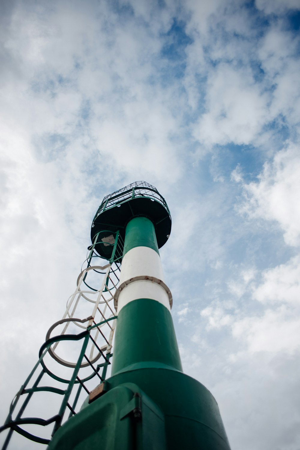 a green and white tower with a sky background