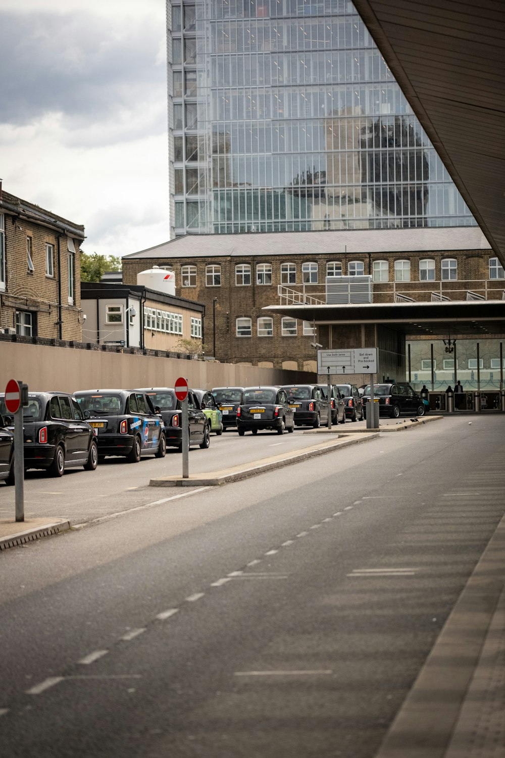 a city street lined with parked cars next to tall buildings