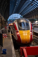 a yellow and red train pulling into a train station