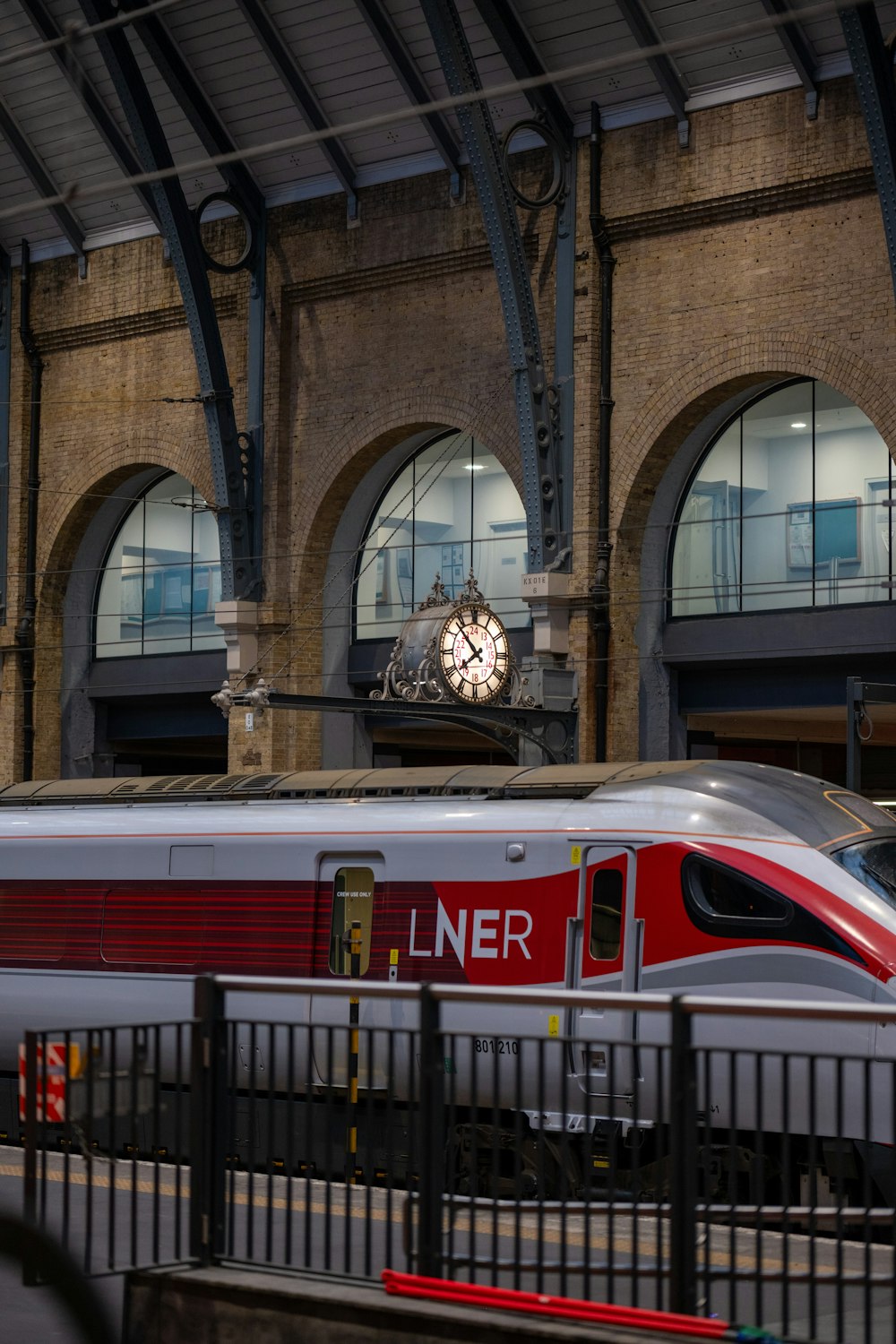 a silver and red train traveling past a train station