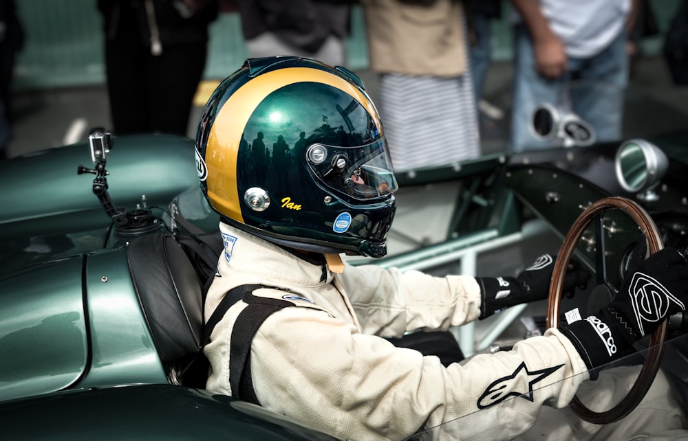 a man sitting in a green car with a helmet on