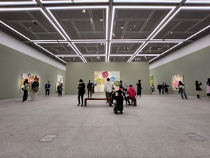 A clean, minimalist art gallery room featuring contemporary paintings with vibrant colors.