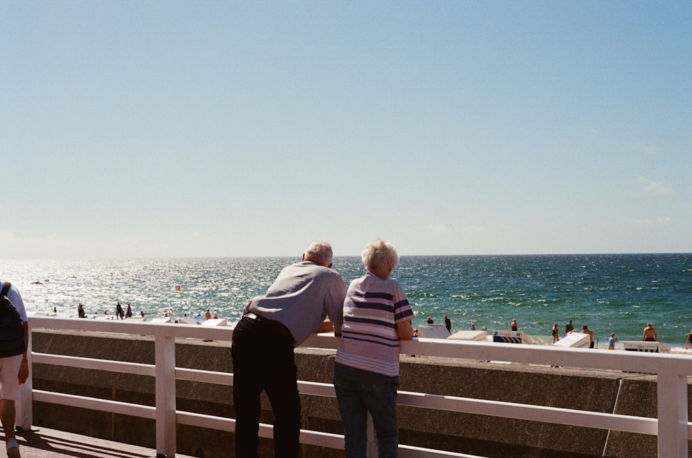 a group of people standing on a pier next to the ocean