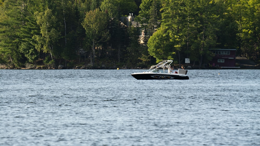 a boat traveling across a lake surrounded by trees