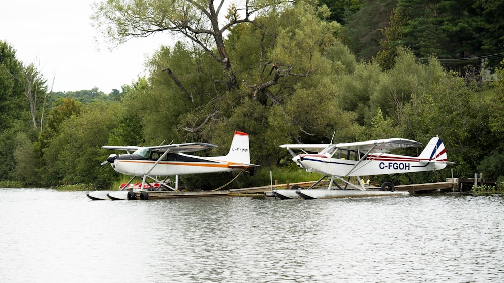 a couple of small planes sitting on top of a body of water