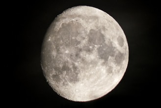 A close-up view of the moon with visible craters and surface details, illuminated against a dark night sky.