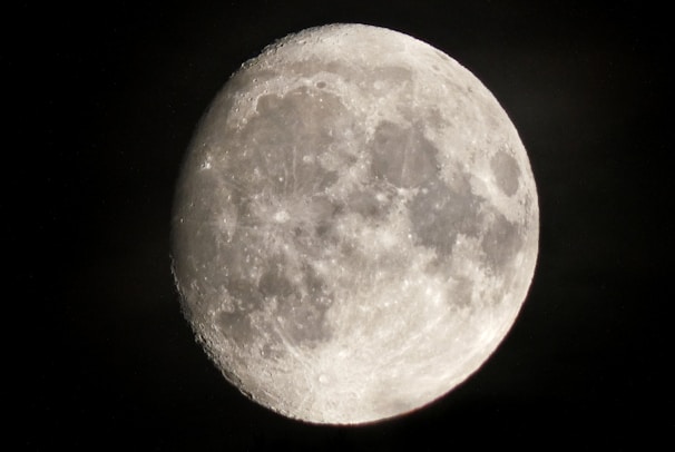 A close-up view of the moon with visible craters and surface details, illuminated against a dark night sky.