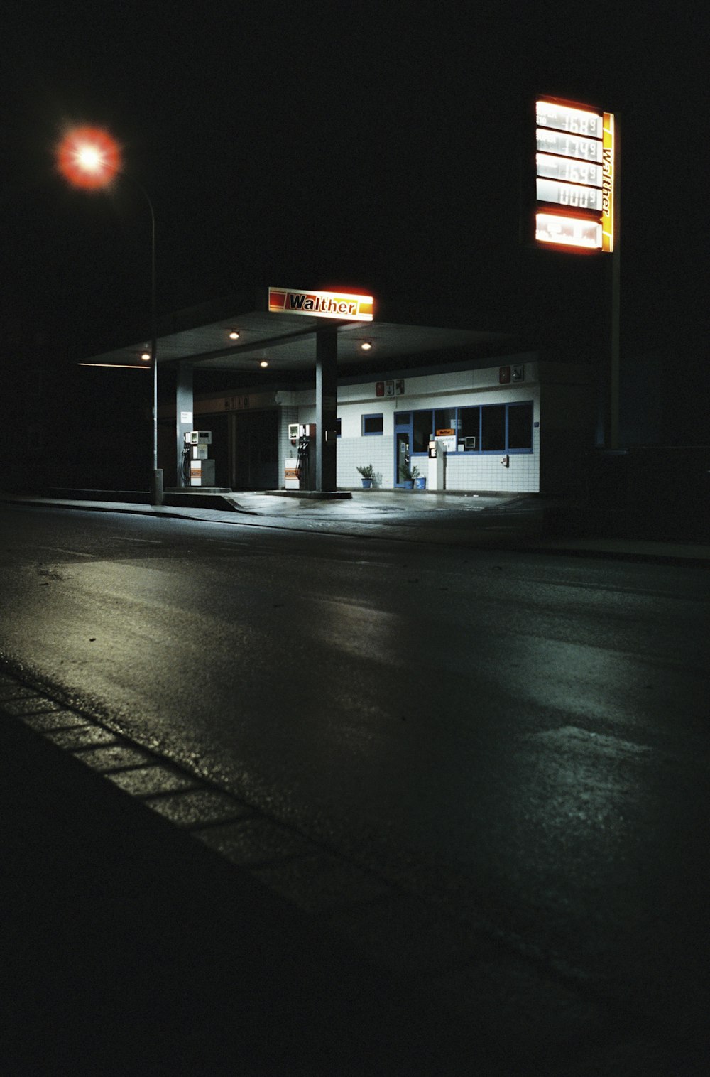 a gas station at night with a lit up sign