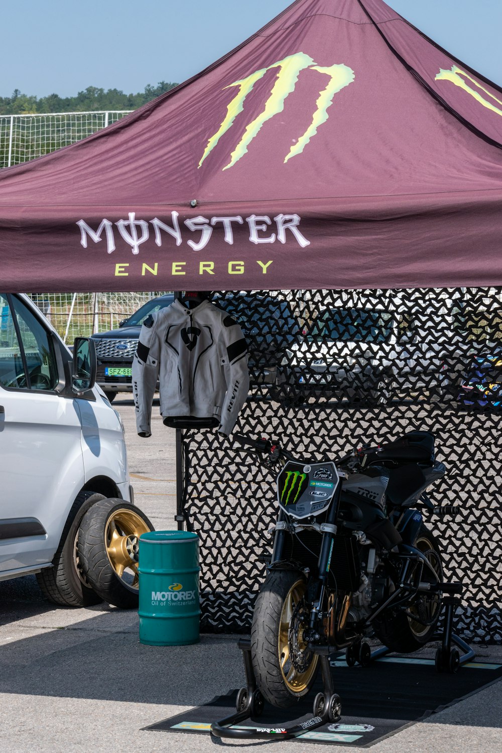 a motorcycle parked under a tent next to a white van