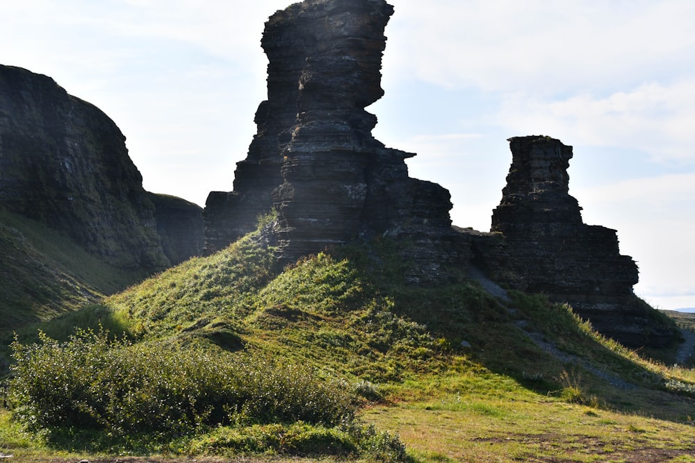 a large rock formation sitting on top of a lush green hillside