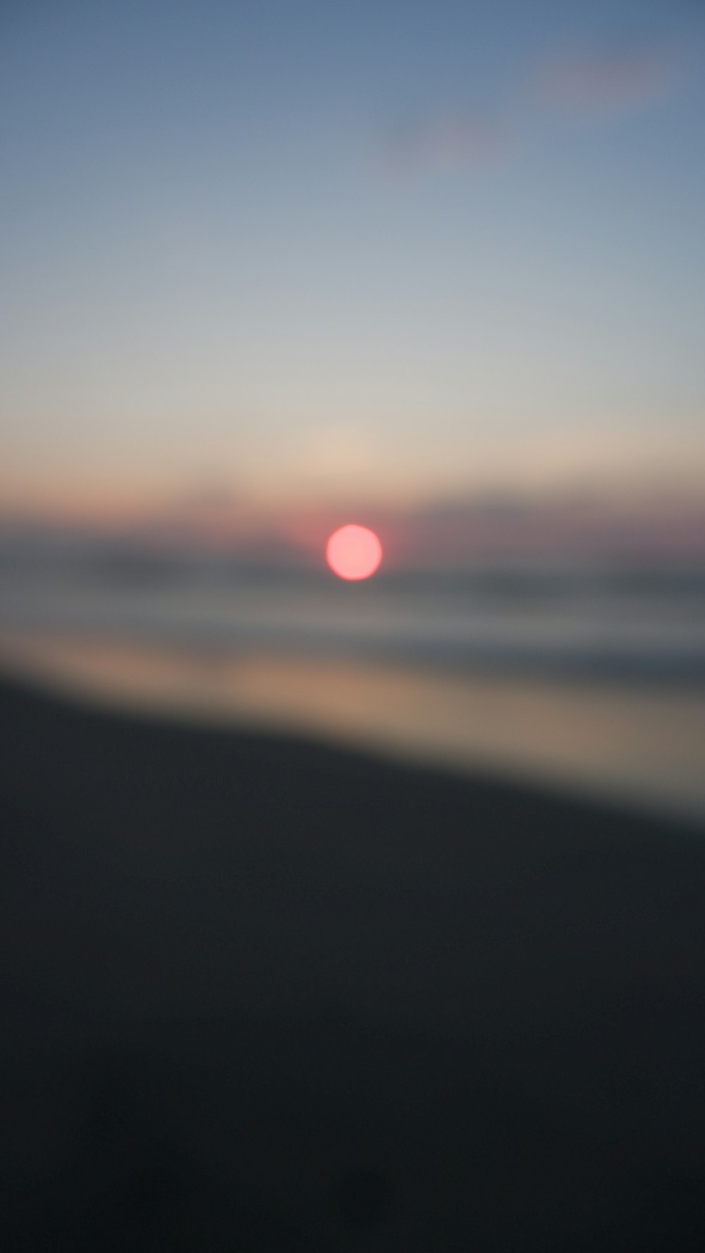 a blurry photo of the sun setting over the ocean