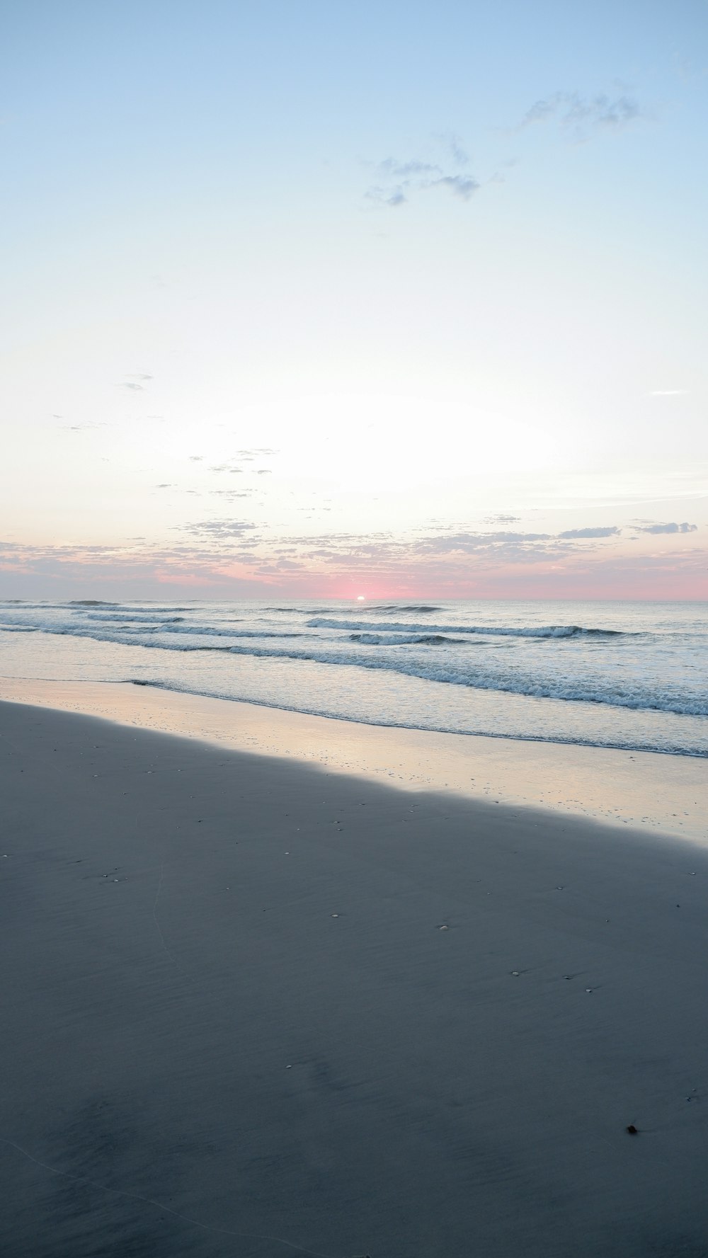 a person walking on a beach with a surfboard