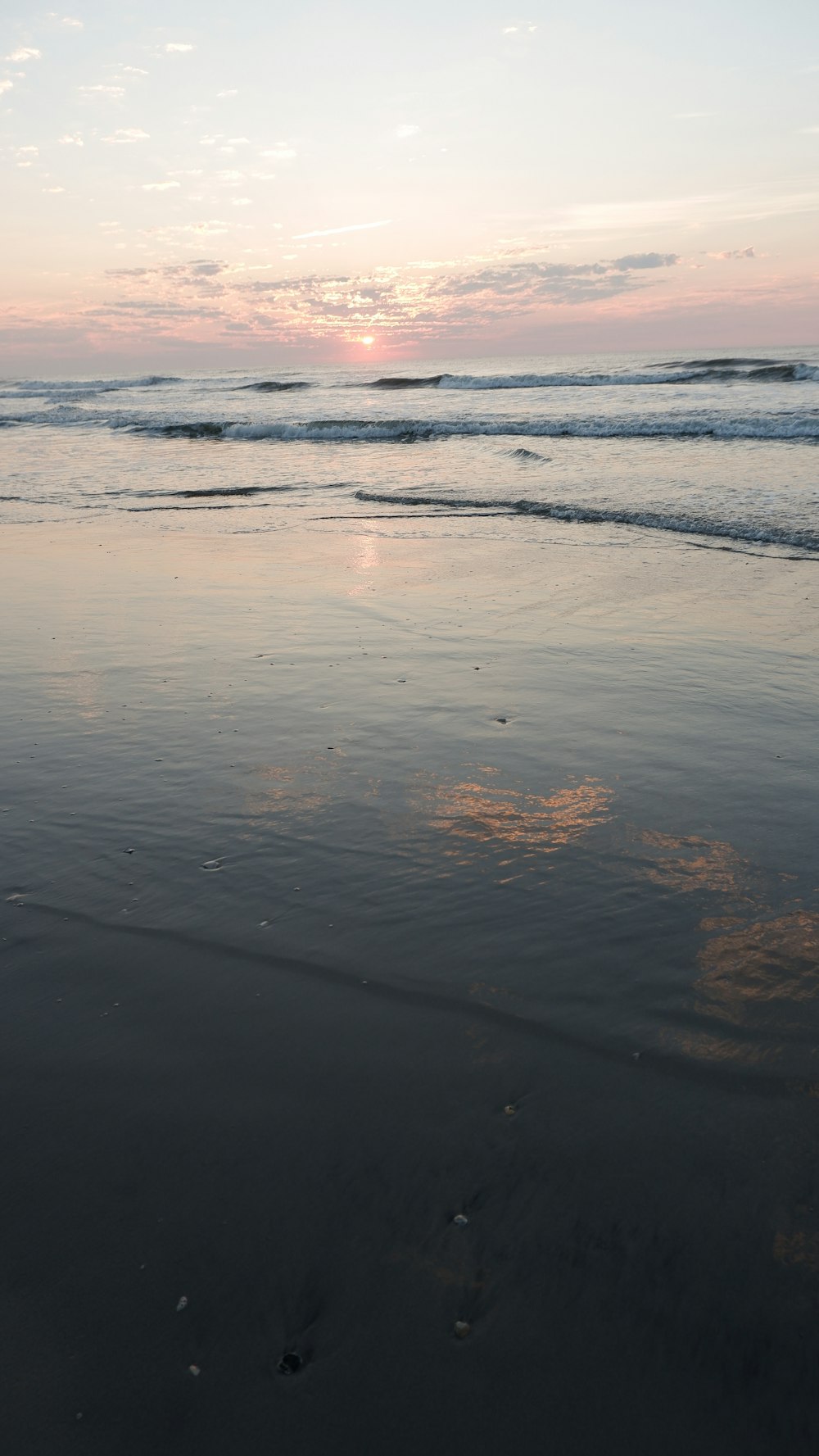 the sun is setting over the water at the beach