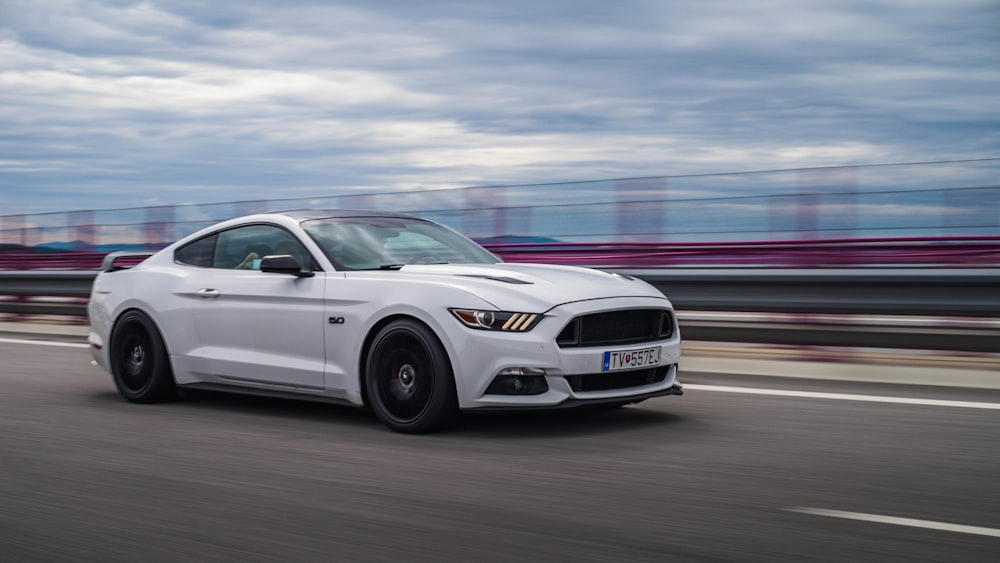 a white ford mustang driving down a highway